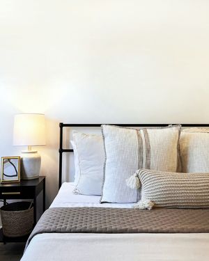 A neatly made bed with crisp white linens and a warm bedside lamp.