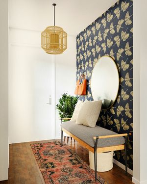A tidy entryway with a bench, a round mirror and a runner rug.