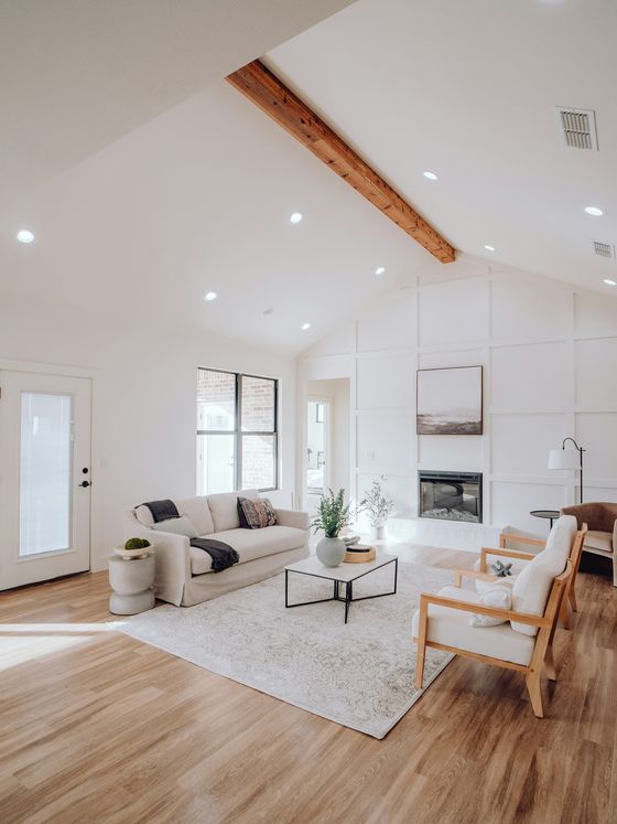 A bright living room with warm wood floors, a vaulted ceiling and daylight coming through tall windows.